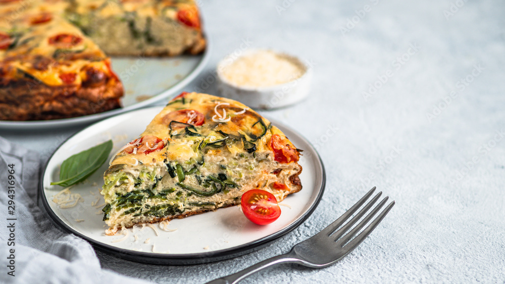 Zucchini pie and ingredients on gray background, copy space. Piece of delicious savory pie with zucchini, tomatoes, herbs and cheese. Idea and recipe for healthy baking and lot to harvest of zucchini Zucchini pie and ingredients on gray background, copy space. Piece of delicious savory pie with zucchini, tomatoes, herbs and cheese. Idea and recipe for healthy baking and lot to harvest of zucchini