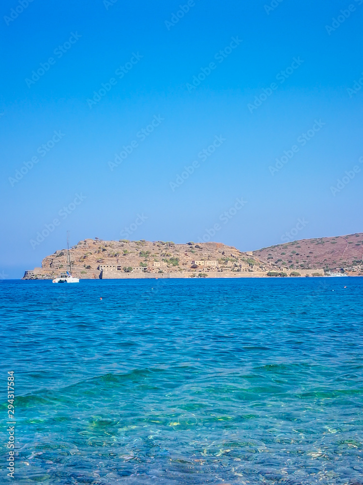 Spinalonga island with blue sky and transparent sea. Elounda, Spinalonga, Crete, Greece. Traveling at Crete, summer vacations and destinations. Copy space for text.