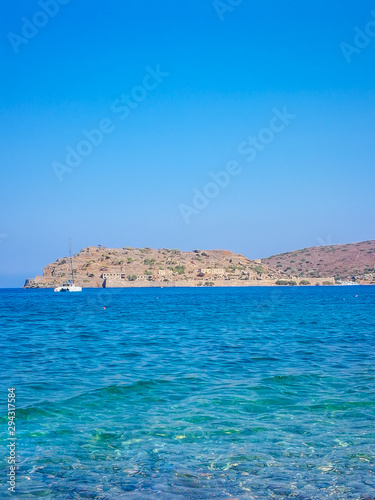 Fototapeta Naklejka Na Ścianę i Meble -  Spinalonga island with blue sky and transparent sea. Elounda, Spinalonga, Crete, Greece. Traveling at Crete, summer vacations and destinations. Copy space for text.