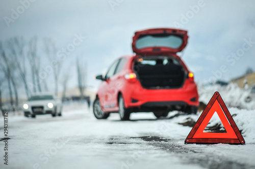 Car red triangle in winter. Emergency sign. Broken car on highway. Warning triangle on snow after car breakdown.