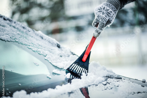 Clean car window from snow. Winter windshield car cleaning. Removing snow from window. photo