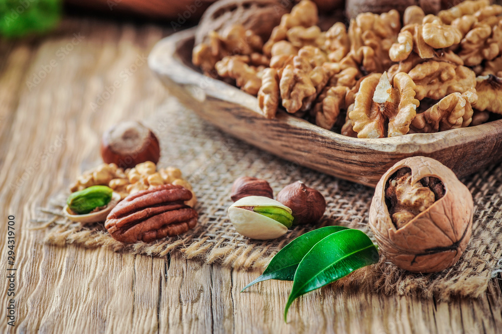 Nuts mixed in wooden bowl. Nuts on wood table with color background Nuts mixed in wooden bowl. Nuts on wood table with color background