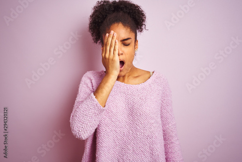 Young african american woman wearing winter sweater standing over isolated pink background Yawning tired covering half face, eye and mouth with hand. Face hurts in pain.