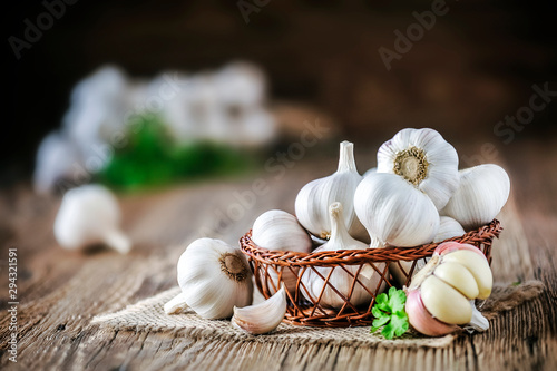 Garlic bulbs in wooden basket on rustic old table. Fresh gralic cloves. Pile of garlic on jute.