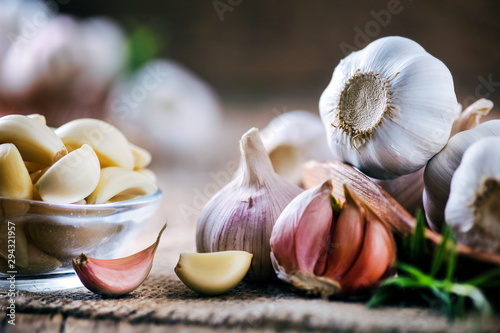 Garlic cloves on rustic table. Garlic in wooden bowl. Fresh peeled garlic and  bulbs. photo