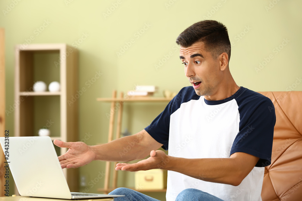 Shocked young man with laptop at home