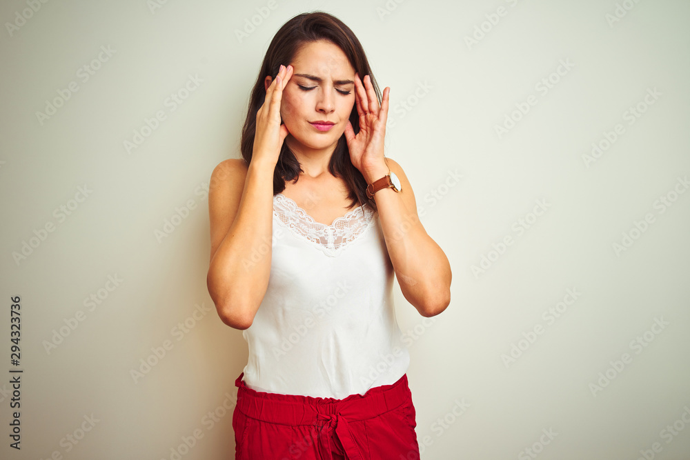 Young beautiful woman wearing t-shirt standing over white isolated background with hand on head for pain in head because stress. Suffering migraine. Young beautiful woman wearing t-shirt standing over white isolated background with hand on head for pain in head because stress. Suffering migraine.