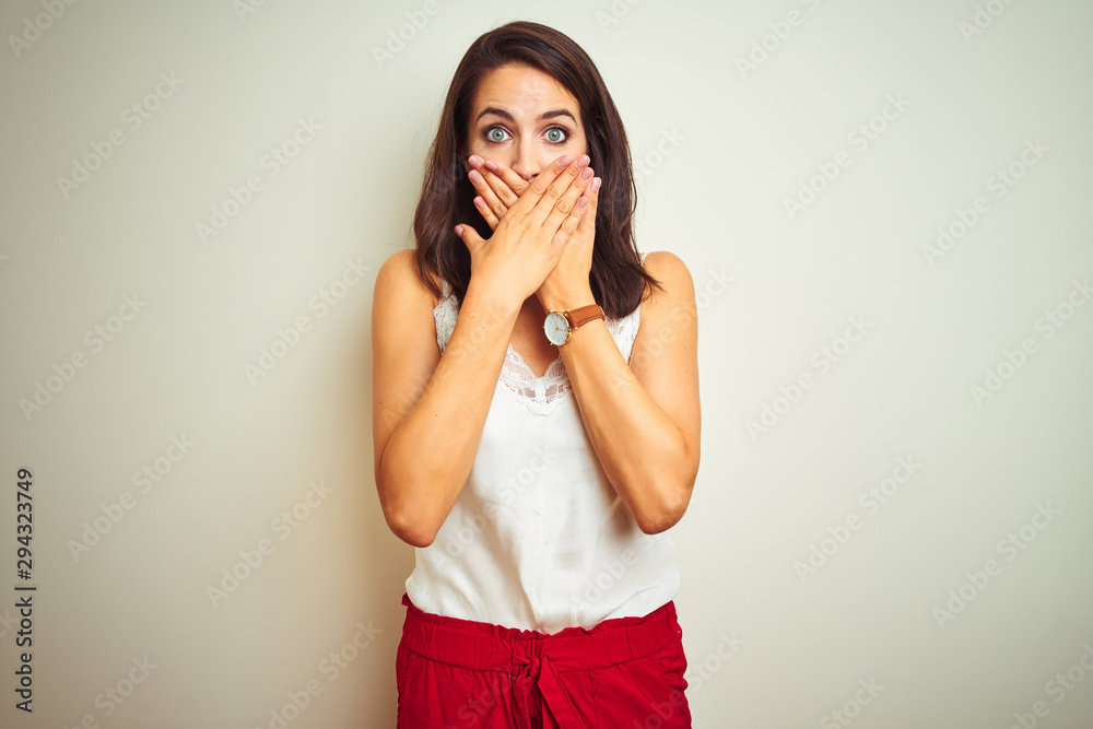 Young beautiful woman wearing t-shirt standing over white isolated background shocked covering mouth with hands for mistake. Secret concept. Young beautiful woman wearing t-shirt standing over white isolated background shocked covering mouth with hands for mistake. Secret concept.