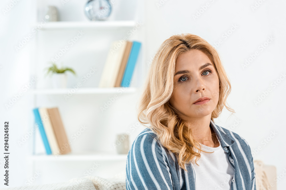 sad woman with bad mood looking at camera in living room sad woman with bad mood looking at camera in living room
