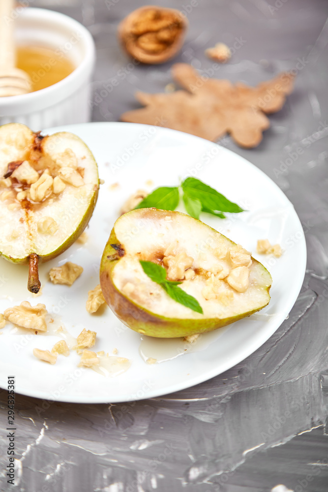 Tasty roast pears with honey and walnuts on white plates on grey background table. Tasty roast pears with honey and walnuts on white plates on grey background table.