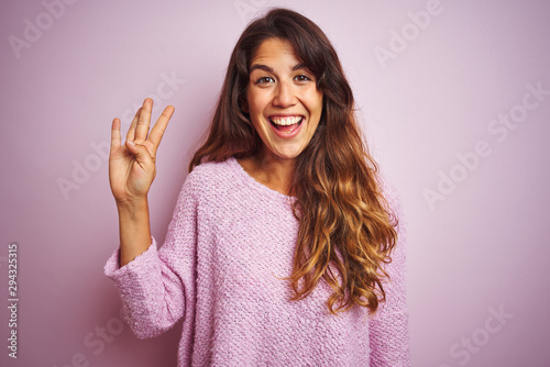 Young beautiful woman wearing sweater standing over pink isolated background showing and pointing up with fingers number four while smiling confident and happy.