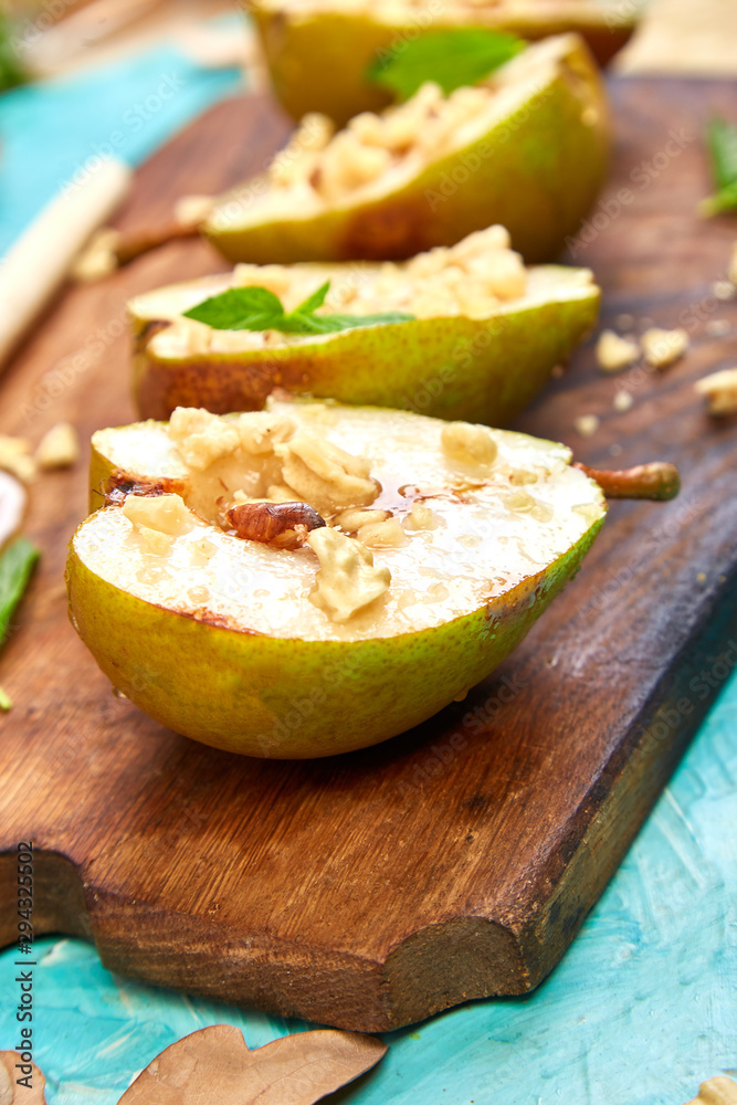 Tasty roast pears with honey and walnuts on wooden board on blue background table. Tasty roast pears with honey and walnuts on wooden board on blue background table.