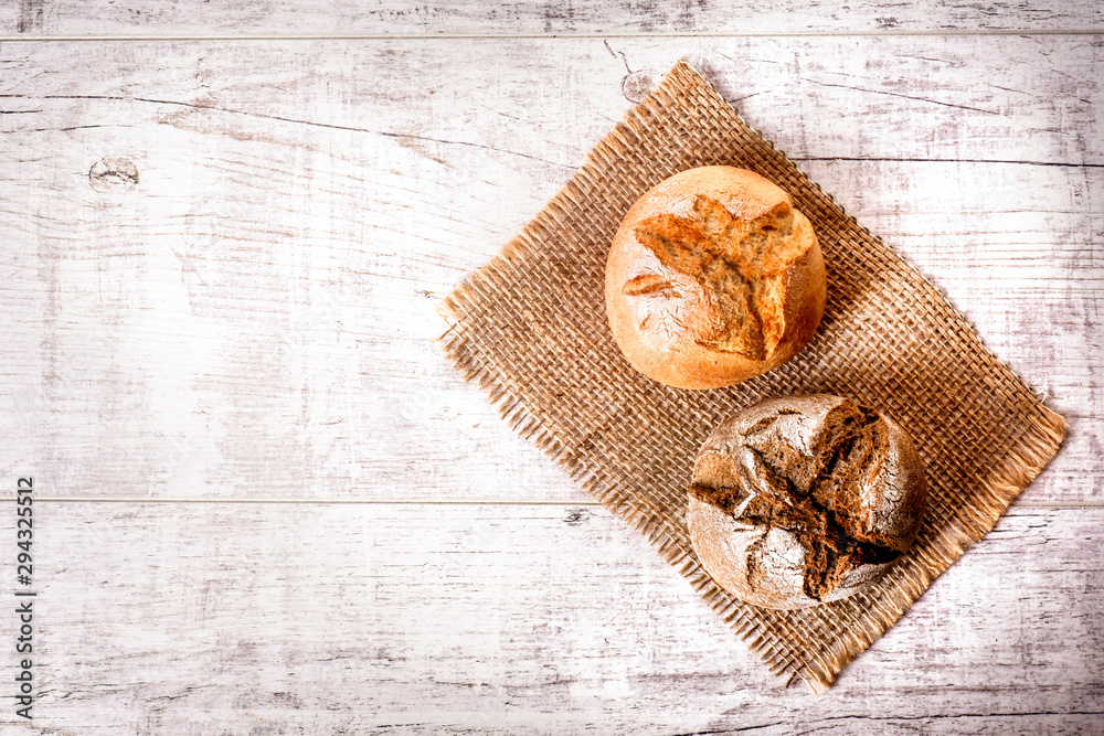Fresh roll bread on white table. Tasty dark and light buns on jute. Small bread on rustic table. Fresh roll bread on white table. Tasty dark and light buns on jute. Small bread on rustic table.