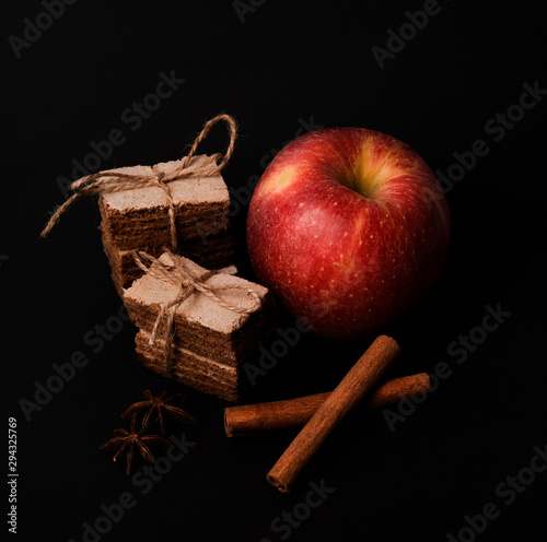 Apple pastila and cinnamon and star anise isolated on black background. Healthy snack concept. Slices of pastila tied with a twine and red apple photo