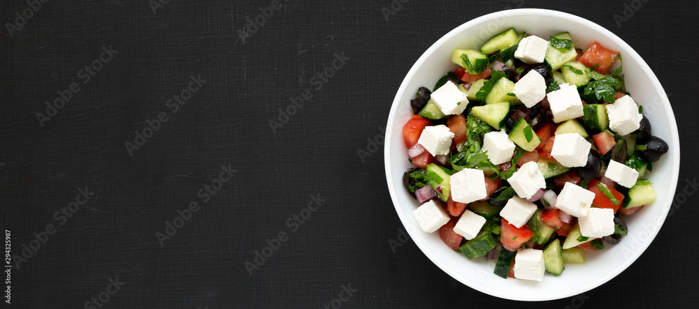 Homemade Shepherd's salad with cucumbers, feta and parsley in a white bowl on a black surface, top view. From above, overhead, flat lay. Space for text. Homemade Shepherd's salad with cucumbers, feta and parsley in a white bowl on a black surface, top view. From above, overhead, flat lay. Space for text.
