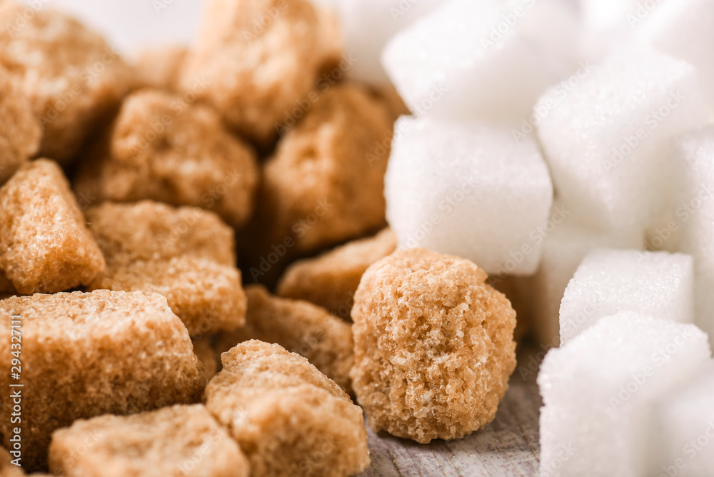 Brown sugar cubes on white rustic table. Pile of white sugar cubes. Brown sugar cubes on white rustic table. Pile of white sugar cubes.
