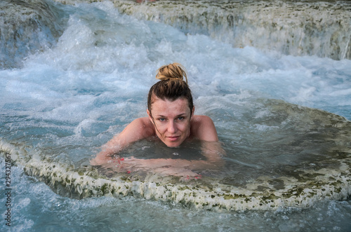 Young charming girl bathes in the healing thermal mineral springs in the resort of Saturnia Italy