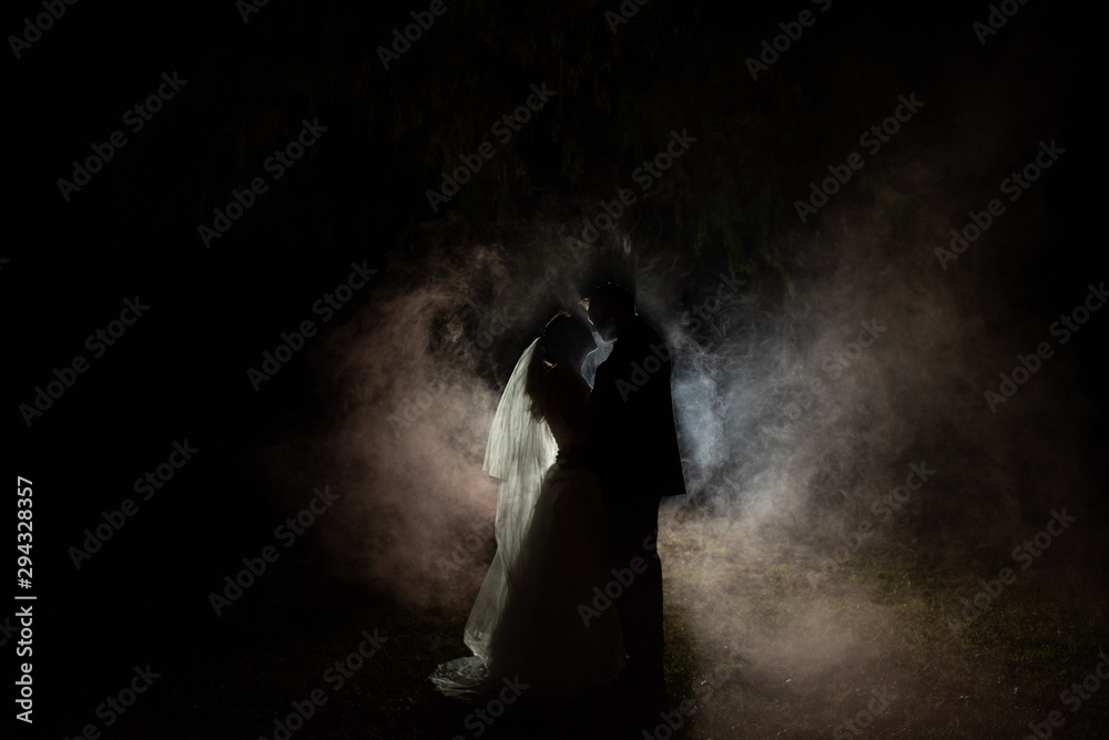 silhouette of a bride and groom at night with a smokey background silhouette of a bride and groom at night with a smokey background