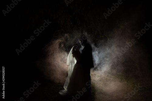silhouette of a bride and groom at night with a smokey background