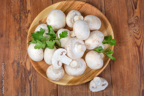 Cultivated mushrooms on wooden dish on rustic table, top view