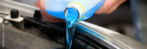 Male hands hold bottle of blue antifreeze in their hands. Liquid is poured into the throat at miovy temperatures self replacement at home photo