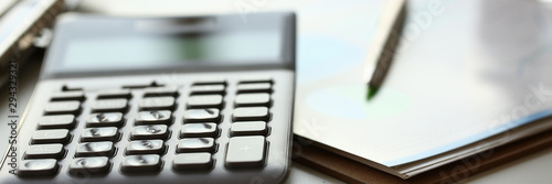 Silver calculator with gray keyboard is lying on desk graph and pen office setting. Calculation of family expenses social income population freelance irs situation growth research concept photo