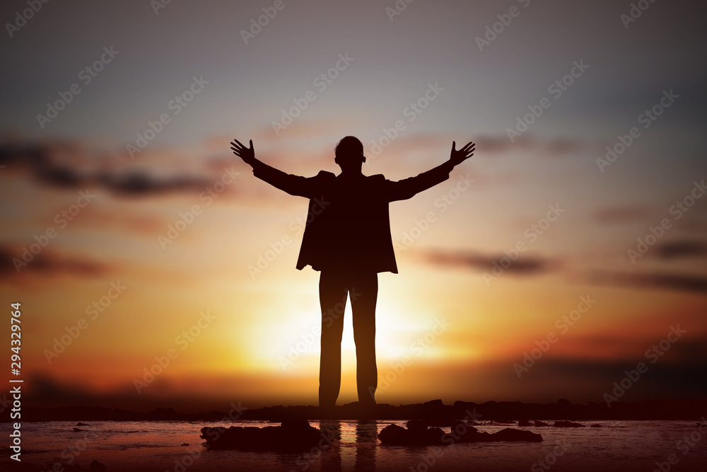Silhouette of businessman raised hands and praying to god