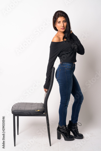 Full body shot of young beautiful Persian woman leaning on the chair