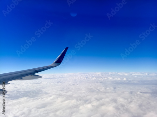 Wing of the plane on blue sky background. Airplane Wing in Flight from window, blue sky. Travel concept idea.