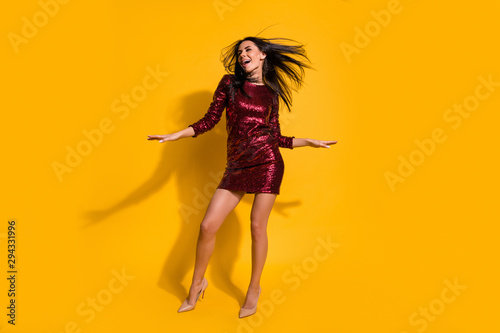 Full length photo of amazing lady with flying hairdo and perfect slim shapes dancing at disco party wear short shine red dress isolated yellow color background
