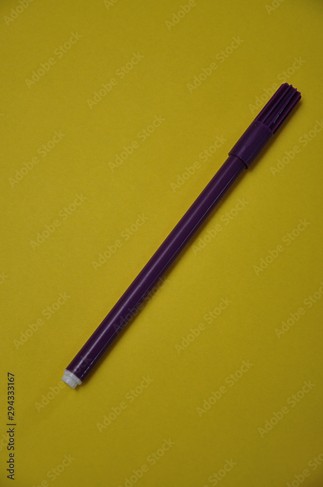 A purple pen isolated on a yellow background A purple pen isolated on a yellow background