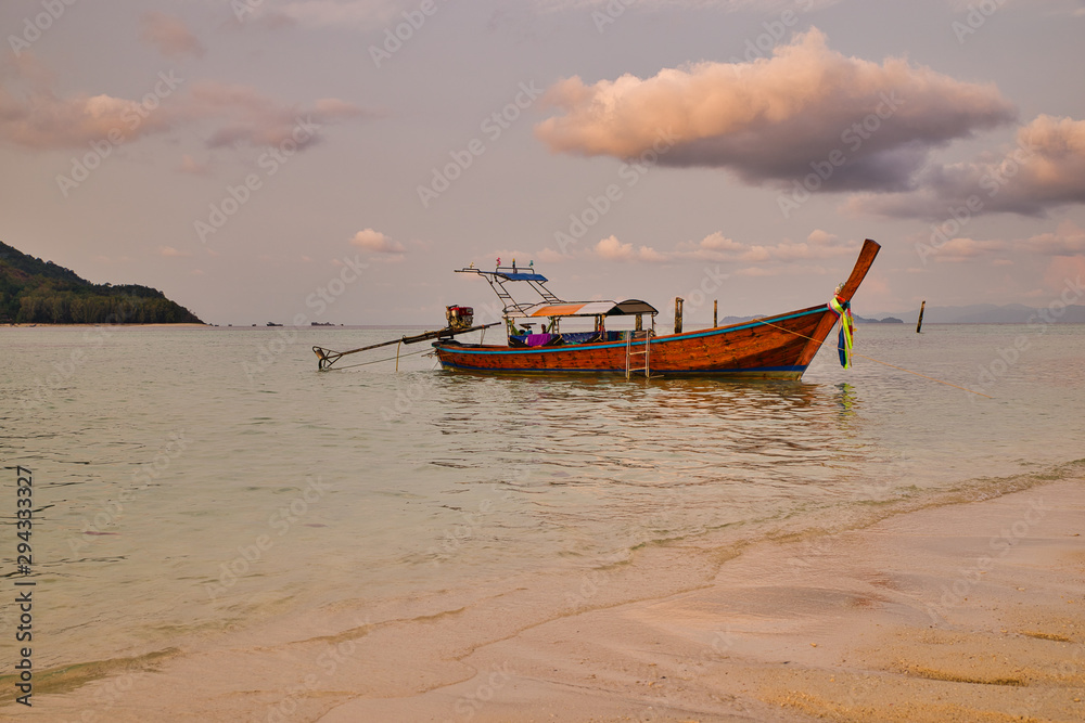 Boat or Taxi moored in The beach in Thailand on a summer day with sun and clouds. Also called Longtails.