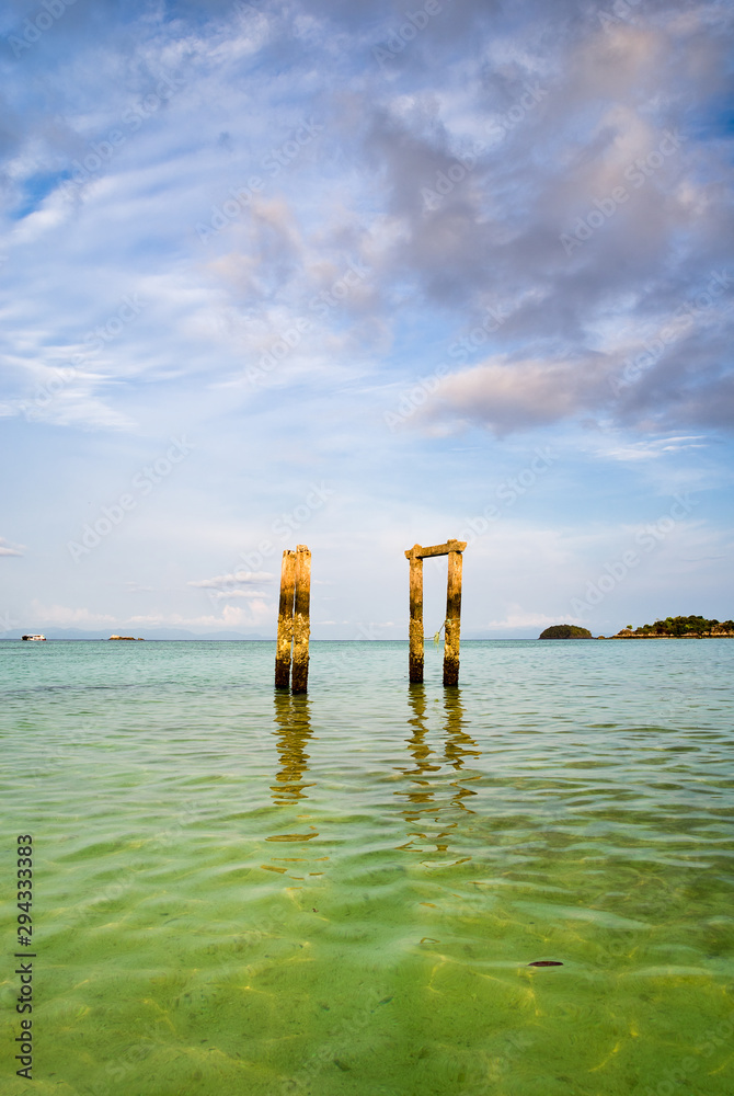 Concrete pillars of an old abandoned jetty on turquoise water beach of an island of Thailand