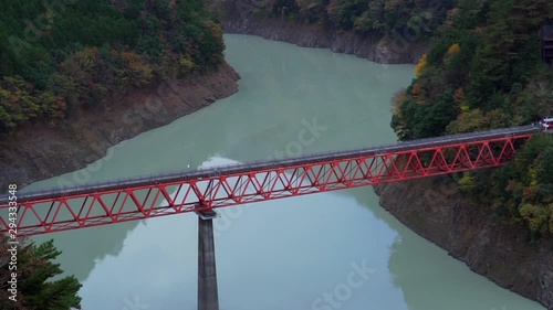 Train runing on red railway over lake to Okuoikojo train station in Shizuoka Japan during autumn with beautiful scenary of mountain and fall foliage colors. photo