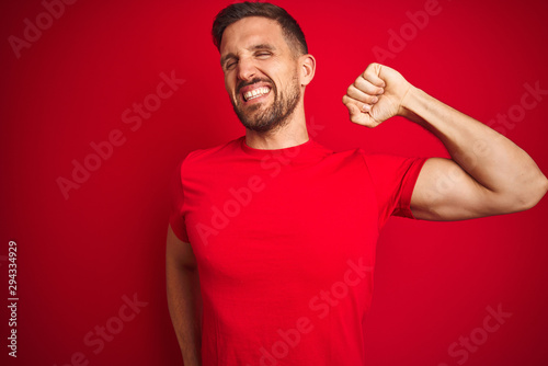 Young handsome man wearing casual t-shirt over red isolated background stretching back, tired and relaxed, sleepy and yawning for early morning