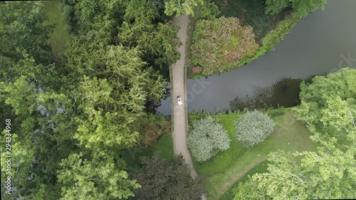 Aerial Birdview Slowmotion of a Young Millenial Wedding Couple standing on a Small Bridge surrounded by Trees photo