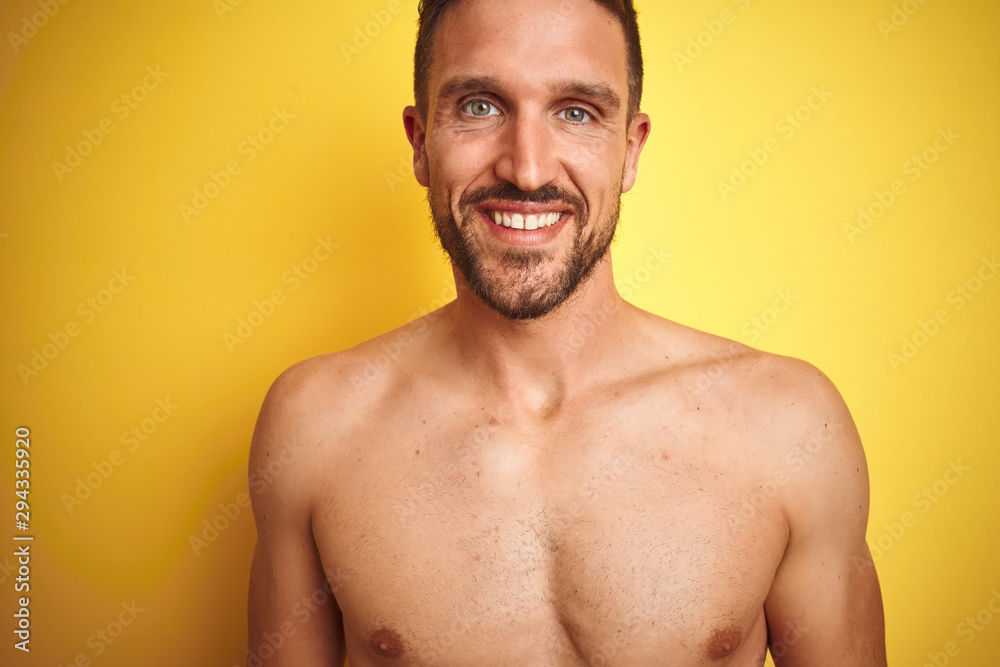 Sexy young shirtless man showing nude fitness chest over yellow isolated background with a happy and cool smile on face. Lucky person.