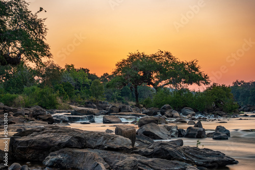 Sunset ultra long exposure in Malawi river with trees and rocks