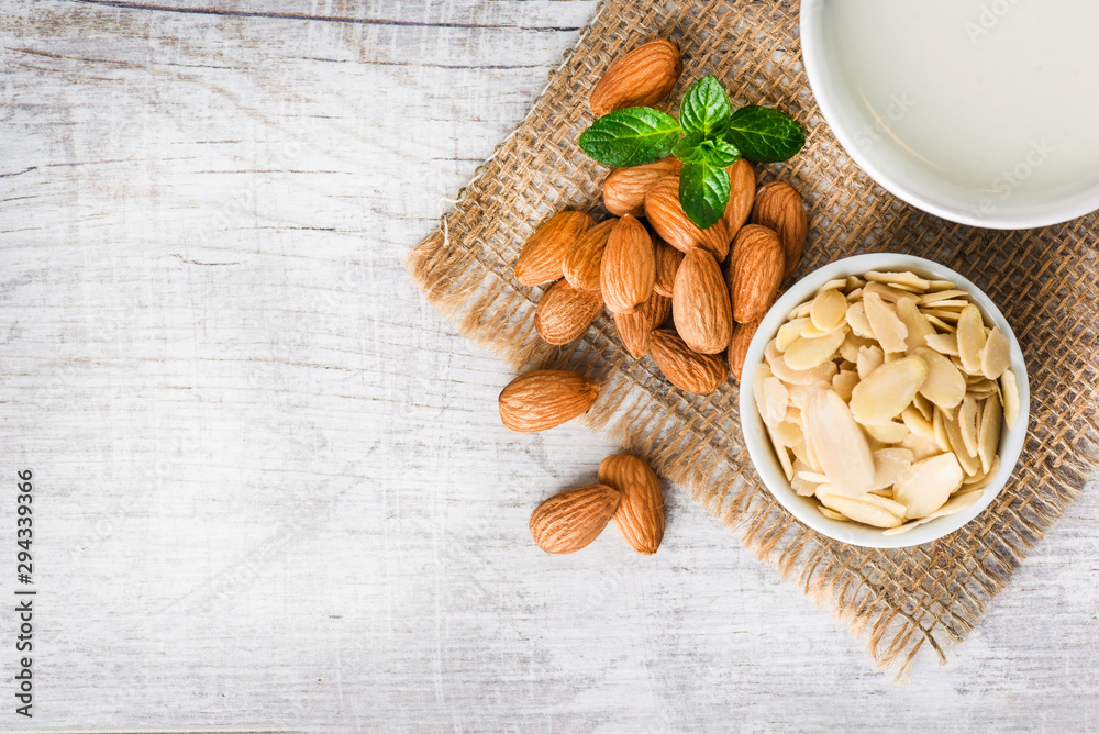 Almonds nuts and peeled almond on white table on jut. Almonds with milk in cup. Top view of almonds nuts. Almonds nuts and peeled almond on white table on jut. Almonds with milk in cup. Top view of almonds nuts.