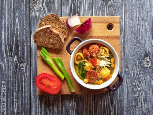 Spicy chorizo sausage stew with vegetables and greens, top view. 