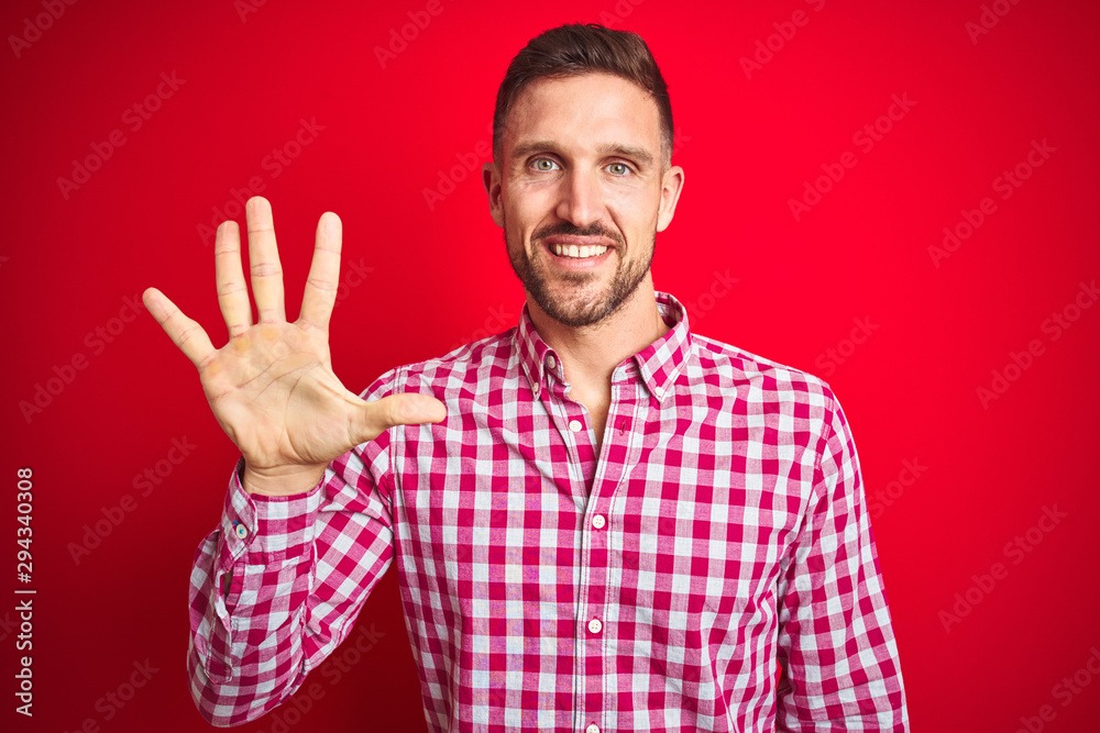Fototapeta premium Young handsome man over red isolated background showing and pointing up with fingers number five while smiling confident and happy.