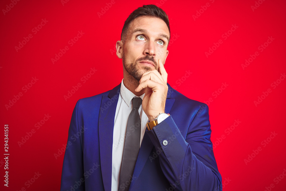 Young handsome business man over red isolated background with hand on chin thinking about question, pensive expression. Smiling with thoughtful face. Doubt concept. Young handsome business man over red isolated background with hand on chin thinking about question, pensive expression. Smiling with thoughtful face. Doubt concept.