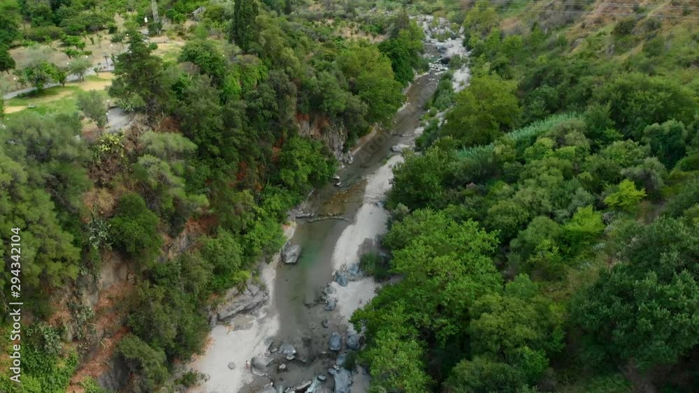 4K AERIAL DOLLY IN: Drone flying above Alcantara Gorges, an impressive channel of lava columns eroded naturally into ravines, canyons and caves. A view over the river and its crystal water and trees 4K AERIAL DOLLY IN: Drone flying above Alcantara Gorges, an impressive channel of lava columns eroded naturally into ravines, canyons and caves. A view over the river and its crystal water and trees
