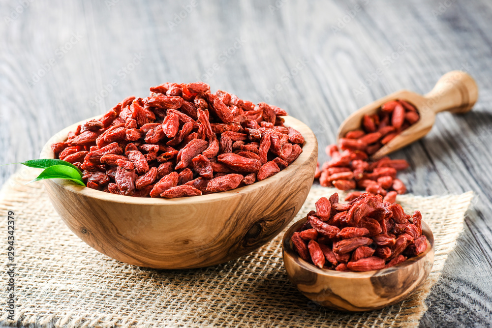 Goji fresh fruits seeds in wooden bowl with scoop ful of goji. Goji on table. Goji fresh fruits seeds in wooden bowl with scoop ful of goji. Goji on table.