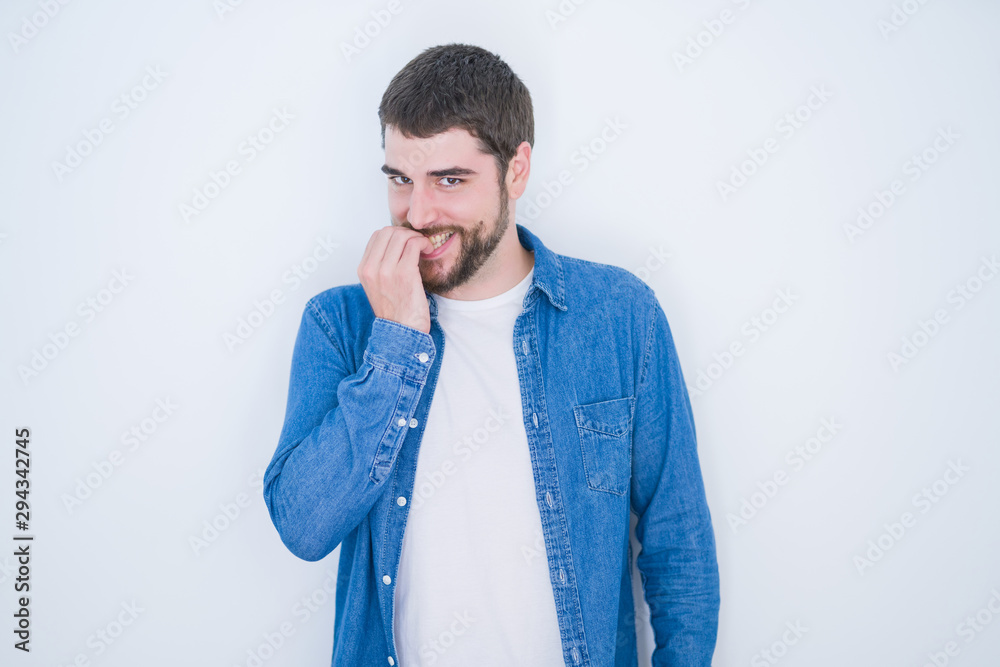 Young handsome hispanic man wearing denim jacket over white isolated background looking stressed and nervous with hands on mouth biting nails. Anxiety problem. Young handsome hispanic man wearing denim jacket over white isolated background looking stressed and nervous with hands on mouth biting nails. Anxiety problem.
