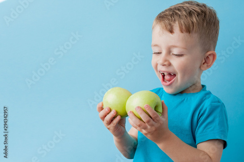 Little Boy Holding an Apples in his hands on blue background, diet and exercise for good health concept