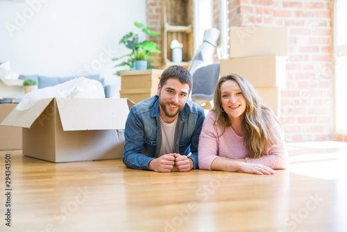 Young beautiful couple in love relaxing lying on the floor together with cardboard boxes around for moving to a new house