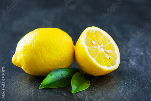 Fresh lemons on dark stone table. Ripe lemon from top view with green leaves. Fresh ripe lepon concept.