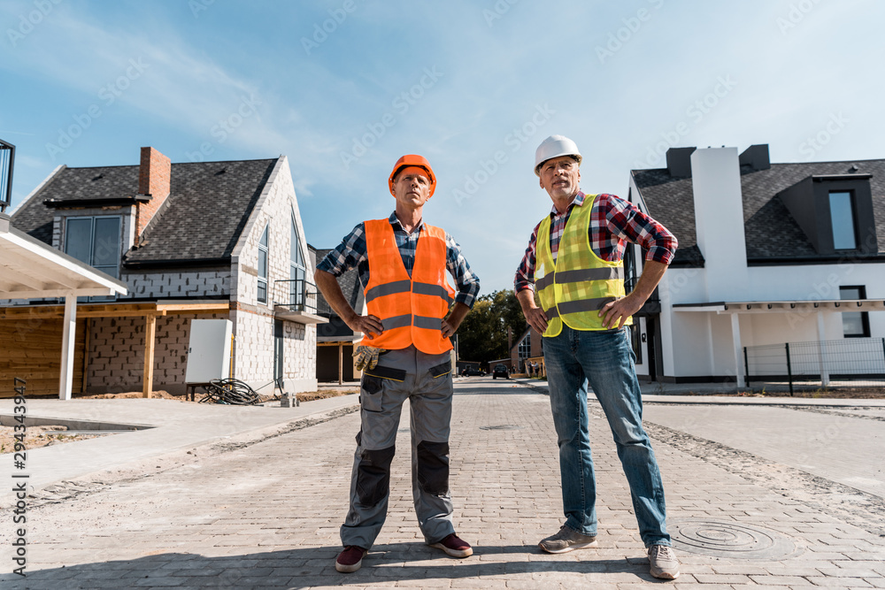 middle aged builders standing with hands on hips outside