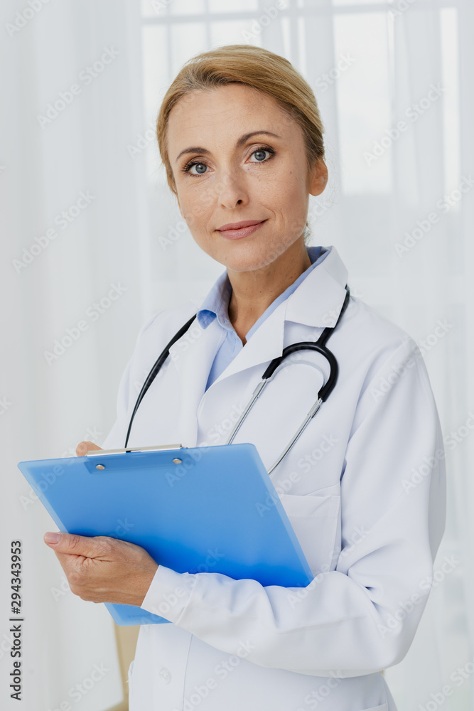Doctor holding clipboard looking at camera